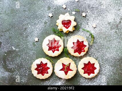 Albero di Natale o Capodanno realizzato con biscotti austriaci Linzer con marmellata e spolverati con zucchero in polvere su fondo di pietra verde. Festa, celebrazione e. Foto Stock