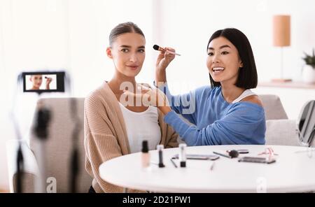 Donna asiatica facendo trucco per il suo modello Foto Stock