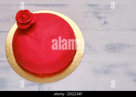 Torta rossa ricoperta di marzepan o mastice e decorata con un fiore, spazio copia Foto Stock