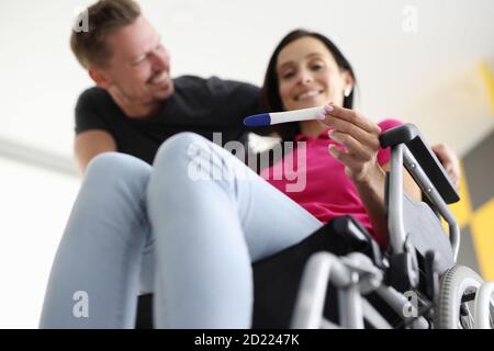 La donna disabile in sedia a rotelle sta tenendo un test con il marito a casa. Foto Stock