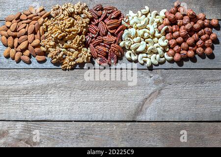 Vari dadi su sfondo di legno. Noce, mandorle, nocciole e anacardi, noci pecan. Cibo vegetariano biologico, spuntini salutari. Foto Stock