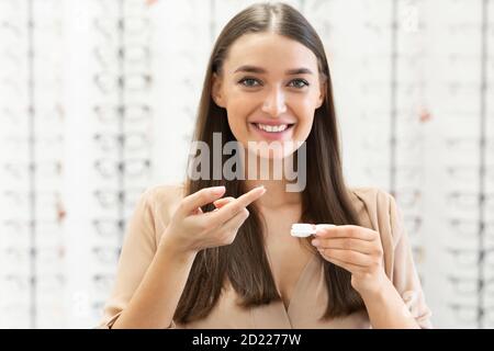 Donna felice che tiene lenti a contatto nel negozio di ottica Foto Stock