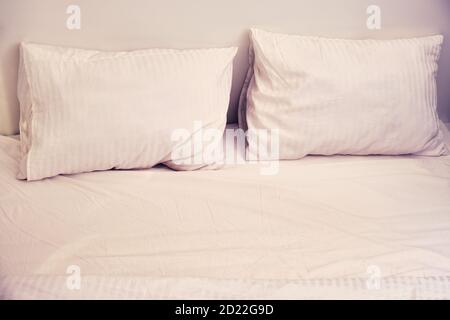 Due cuscini su un letto vuoto bianco la sera Foto Stock