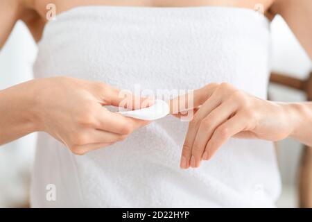 Donna che rimuove la lacca dai chiodi curati con tampone di cotone bianco Foto Stock