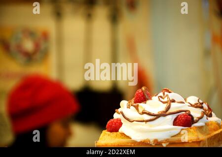 Waffle belgi con panna montata, lamponi e salsa al cioccolato in vendita al mercatino di Natale in Avenue des Champs-Elysees a Parigi. Foto Stock