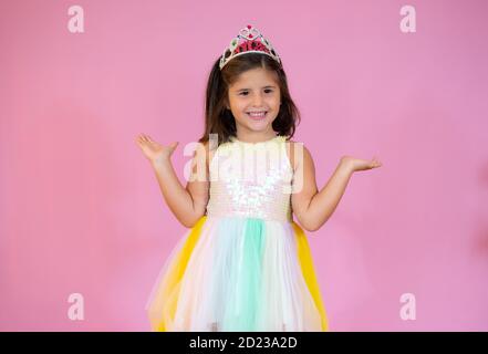 Ragazza in un abito festivo si erge sullo sfondo rosa e sorrisi Foto Stock