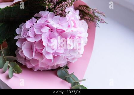 Lussuoso arrangiamento floreale con idrangea rosa, eucalipto, Heather in carta rosa su sfondo bianco. Biglietto d'auguri. Vacanze bouquet.fresh Foto Stock