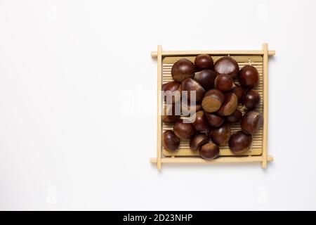 Castagne in vassoio di legno su sfondo bianco. Spuntini autunnali e invernali. Vista dall'alto, spazio fotocopie Foto Stock