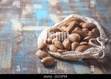 Mandorle in un sacchetto di cotone riutilizzabile su un tavolo di legno. Eco-package, concetto zero rifiuti. Concetto di mandorla con copyspace. Foto Stock