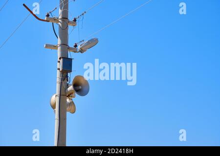Altoparlante sul polo di illuminazione. Mezzi di avvertimento in caso di emergenza. Contro lo spazio di copia di sfondo blu del cielo Foto Stock
