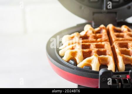 Il processo di preparazione di waffle fatti in casa. Waffle appena sfornati in un ferro da stiro a base di waffle. Foto Stock