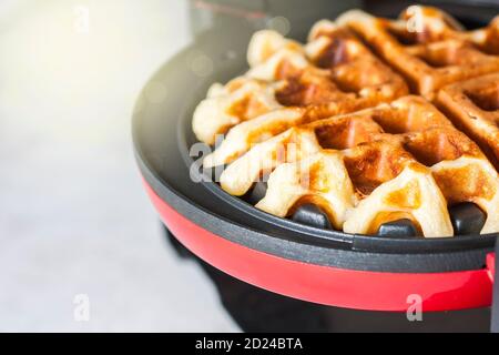 Il processo di preparazione di waffle fatti in casa. Waffle appena sfornati in un ferro da stiro a base di waffle. Foto Stock