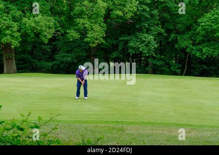 Il golfer maschile si prepara a colpire la sua palla nel buco sul verde al Pinner Hill Golf Club, Pinner, Middlesex. Foto Stock