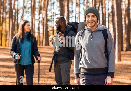 Felice ragazzo zaino in spalla sorridendo sopra i suoi amici parlanti Foto Stock
