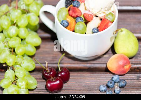 Ciotola di sana Macedonia di frutta fresca con gelato su sfondo di legno. Foto Stock