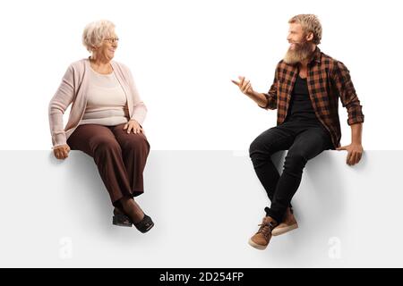 Donna anziana che ascolta un ragazzo sopportato e seduto sopra un pannello bianco isolato su sfondo bianco Foto Stock