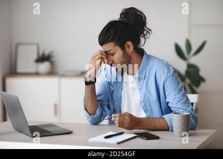 Affaticamento degli occhi. Ha sottolineato Indian Man stanco dopo aver lavorato su laptop in ufficio Foto Stock