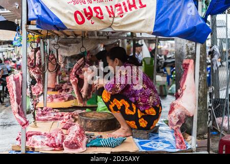 PHU QUOC, VIETNAM - 13 agosto 2019: Una donna commerciante che ha una bevanda nel suo stallino di carne al mercato mattutino di Duong Dong Foto Stock
