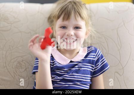 La bambina sorride e tiene in mano il nastro rosso verticale Foto Stock