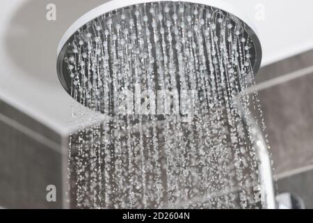 Primo piano di flussi d'acqua in piccoli getti di pioggia metallica doccia in bagno Foto Stock