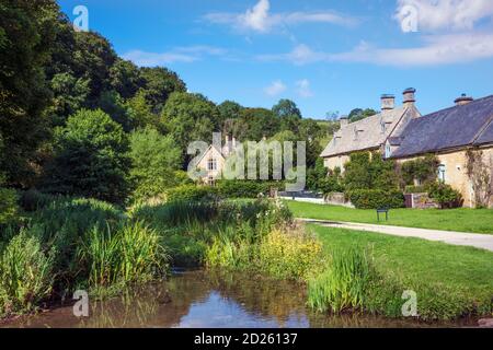 Regno Unito, Gloucestershire, Cotswolds. Vista estiva di un ruscello e cottage tradizionali nel villaggio di Lower Slaughter vicino Stow-on-the-Wold Foto Stock