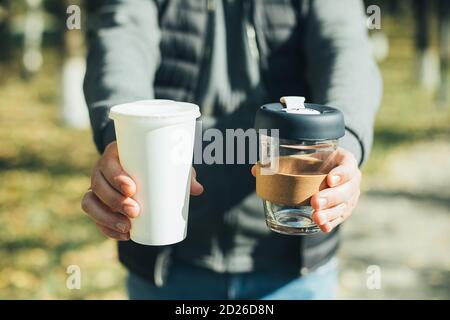 Da uomo con tazza da caffè da asporto e tazza di carta monouso con coperchio in plastica. Scelta consapevole. Concetto di zero sprechi Foto Stock