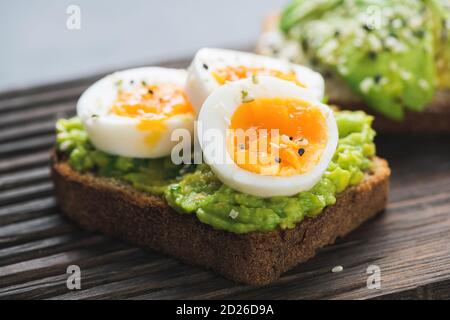 Toast all'avocado con uova su tavola di legno, vista guardaroba Foto Stock