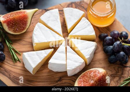 Formaggio Camembert o brie con fichi, uva e miele su tavola di servizio in legno. Piatto di formaggio Foto Stock