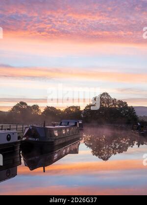 Una splendida alba sul canale di Leeds & Liverpool a Skipton, Yorkshire Dales National Park, mentre le barche dei canali galleggiano sulle acque calme dello specchio. Foto Stock