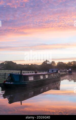 Una splendida alba sul canale di Leeds & Liverpool a Skipton, Yorkshire Dales National Park, mentre le barche dei canali galleggiano sulle acque calme dello specchio. Foto Stock