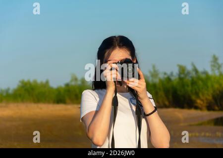 La giovane donna fotografa il paesaggio in una giornata estiva. Professione fotografica. Bella bokeh, messa a fuoco selettiva. Foto Stock