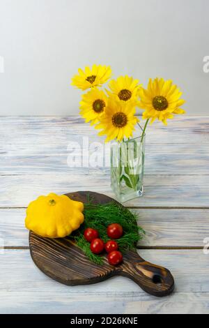 Ancora vita di fiori gialli in vaso di vetro e verdure su tavola di legno. Pomodori ciliegini, frittatine frittate, aneto. Concetto di cibo sano. Foto Stock