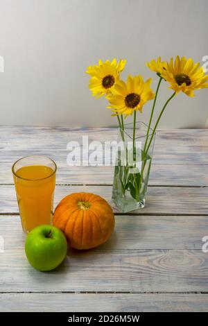 Frullato di zucca e mela, dieta disintossica. Bicchiere di succo, zucca, mela e fiori gialli su sfondo di legno. Concetto di cibo sano. Messa a fuoco selettiva. Foto Stock