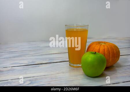 Bicchiere di succo di mela verde appena spremuto e di zucca. Cibo vegano, dieta disintossicante. Concetto di cibo sano. Messa a fuoco selettiva, spazio di copia. Foto Stock