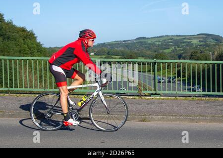 Ciclista maschile equitazione GIGANTE (T-Mobile) sport bianco bici da strada sulla strada di campagna che attraversa il ponte autostradale nella rurale Lancashire, Regno Unito Foto Stock