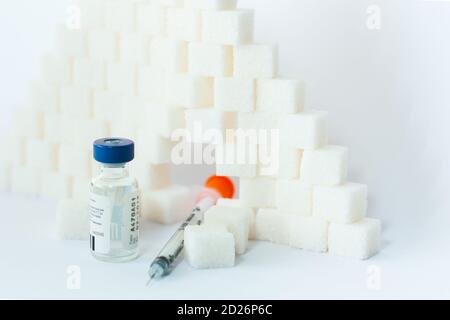 Dipendenza da zucchero, resistenza all'insulina, dieta malsana, piramide a cubetti di zucchero, flaconi di insulina e siringa per la vaccinazione su fondo bianco, diabete Foto Stock