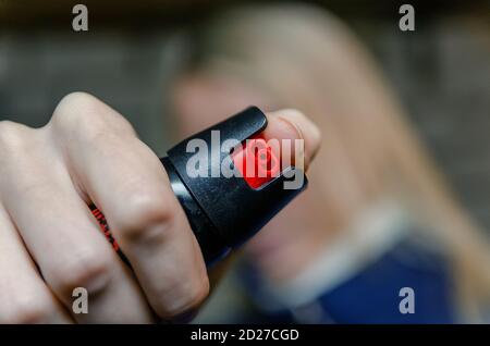 Donna bionda che tiene il pepe spray per auto difesa primo piano Foto Stock