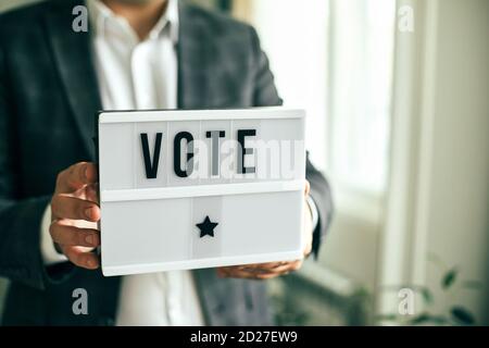 La parola VOTO scritto su lightbox nelle mani degli uomini. Concetto di elezione. Foto Stock