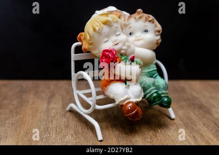 Figurine in ceramica di bambini su una panchina su un legno sfondo Foto Stock