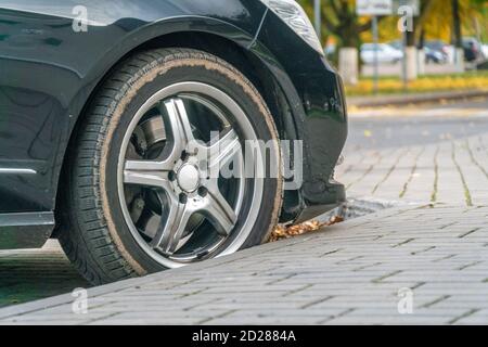 Vista laterale della ruota di un'auto nera parcheggiata in autunno primo piano Foto Stock