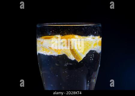 belle fette arancioni di arancio in acqua con bolle su sfondo nero Foto Stock