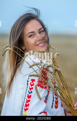 Sliven, Bulgaria - 24 giugno 2018: Una giovane donna che indossa un tradizionale abito popolare bulgaro tenendo orecchie di grano Foto Stock