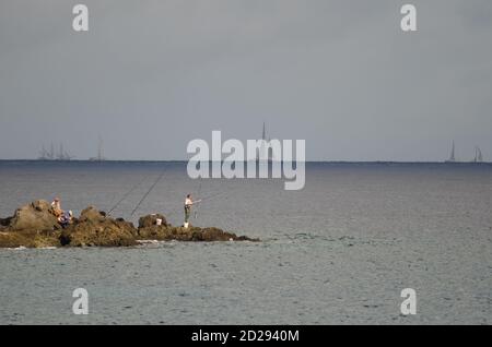 I pescatori e la corsa transatlantica sullo sfondo. Risco Verde. Playa de Arinaga. Aguimes. Gran Canaria. Isole Canarie. Spagna. Foto Stock