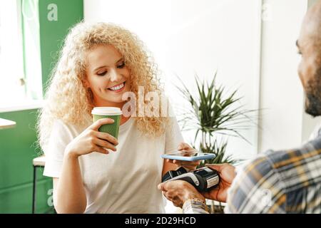 Donna cliente del bar che paga il caffè tramite cellulare telefono con tecnologia senza contatto Foto Stock