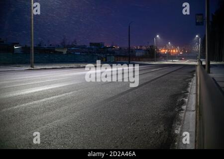 Strada suburbana con luci su una serata invernale di neve Foto Stock