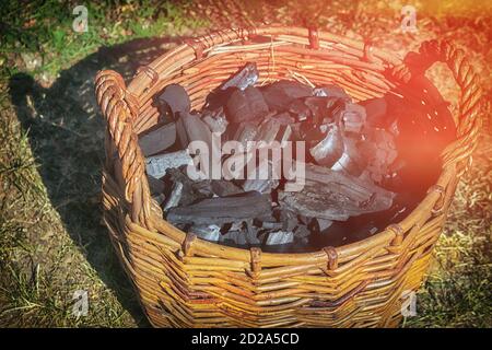 Cestino con carbone sull'erba in una giornata di sole. Foto Stock