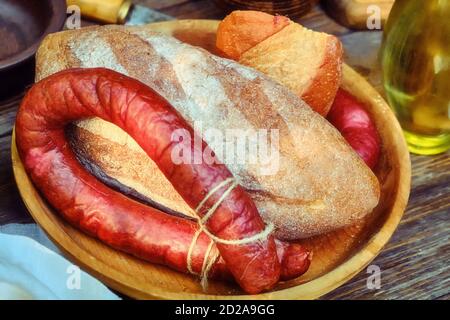 Pane e salsiccia fatti in casa su un tavolo di legno. Cibo retrò, bottiglia di olio d'oliva. Foto Stock