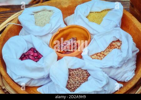 Cereali e spezie in un cesto di vimini, stile di vita. Cereali, fagioli, piselli, riso e pepe in sacchi. Foto Stock