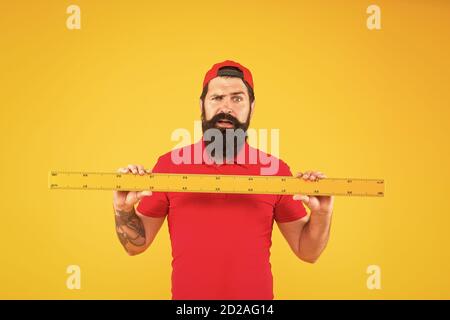 Shop Assistant. Dimensioni perfette. Uomo con bearded con grande strumento di misura. Misurazione con righello. Misurazione delle dimensioni. Misurazione della lunghezza. Taglia i vestiti. Studio studentesco discipline STEM. Attrezzo righello. Foto Stock