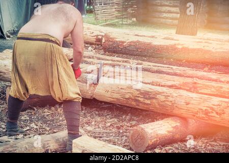 Uomo tagliabaschi in vecchi abiti con un'ascia. Un lumberjack, ascia d'annata per tagliare grandi tronchi. Foto Stock